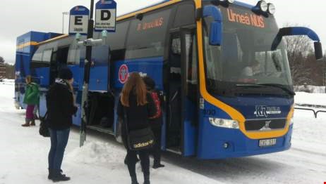 Fyra personer står utanför en blå buss.