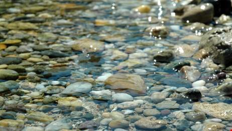 Vatten i bäck som rinner mjukt över hårda stenar